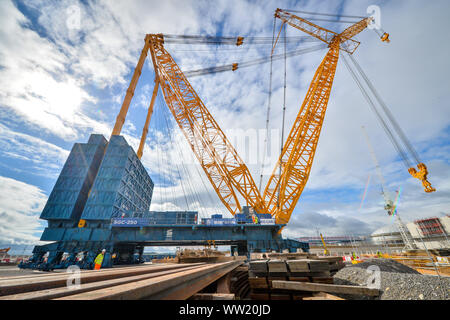 Construction workers are dwarfed as they stand underneath the base of ...