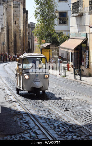 A tuk tuk driving up the cobbled street, Largo da Sé, in Lisbon's old city, the Alfama District. Portugal photographs. Stock Photo