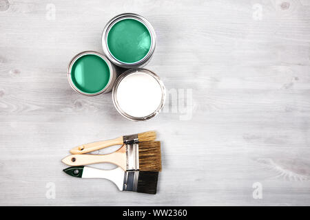Green paint cans and colored brushes on white wooden background Stock Photo