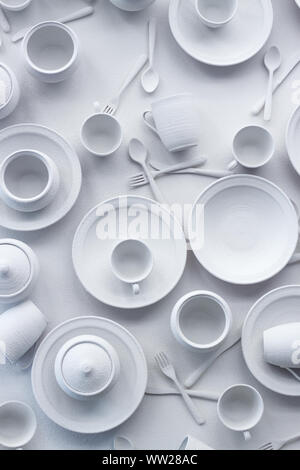Many dishes and appliances are painted white on white surface, the concept of excessive consumption, selective focus Stock Photo