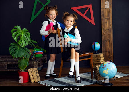 Little twins in school uniform holding books while studying together Stock Photo