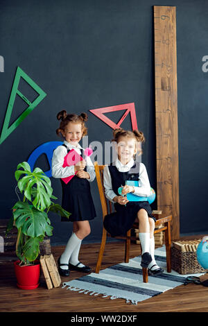 Little twins in school uniform holding books while studying together Stock Photo