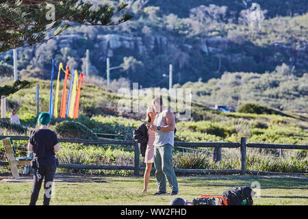 Actors Jake Ryan and Sam Frost plus a member of the filming cast prepare to film an outdoor scene of Home & Away tv series at Palm Beach, Australia Stock Photo