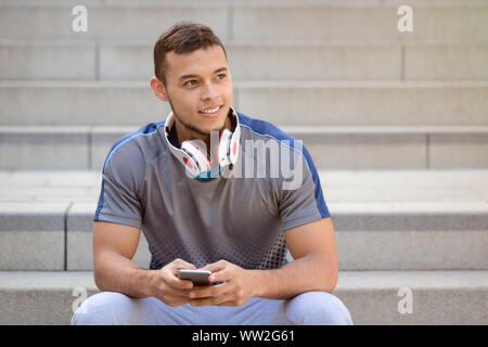 Smartphone cell phone listening to music young latin man looking up listen outdoor Stock Photo