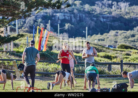 Actors Jake Ryan and Sam Frost plus extras film an outdoor scene of a  training session for the Home & Away tv series at Palm Beach, Australia Stock Photo