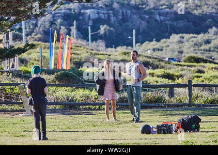 Actors Jake Ryan and Sam Frost plus a member of the filming cast prepare to film an outdoor scene of Home & Away tv series at Palm Beach, Australia Stock Photo