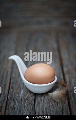 Still life-An egg on white ceramic spoon arranged in a rustic scene, Eggs is beneficial to the body, Food concept. Stock Photo
