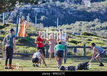 Actors Jake Ryan and Sam Frost plus extras film an outdoor scene of a  training session for the Home & Away tv series at Palm Beach, Australia Stock Photo