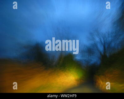 moody twilight image with blurred lines and shapes of trees taken while driving Stock Photo