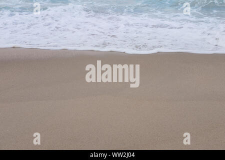 Wave of the sea and white clean foam on the sandy beach with Copy space. Stock Photo