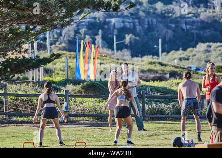 Actors Jake Ryan and Sam Frost plus extras film an outdoor scene of a  training session for the Home & Away tv series at Palm Beach, Australia Stock Photo