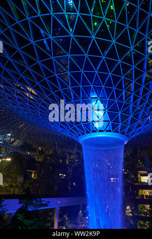 SINGAPORE - CIRCA APRIL, 2019: 40-meter HSBC Rain Vortex, the world’s tallest indoor waterfall at the Jewel Changi Airport at night. Stock Photo