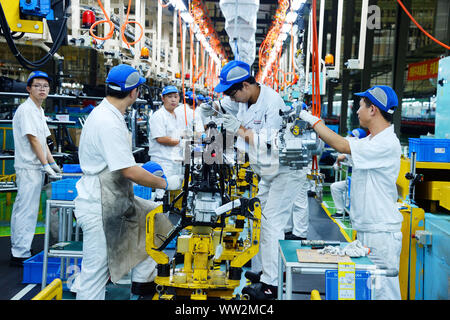 Chinese factory workers assemble motorcycles on the assembly line at the plant of Sundiro Honda Motorcycle Co., Ltd. in Taicang City, east China's Jia Stock Photo