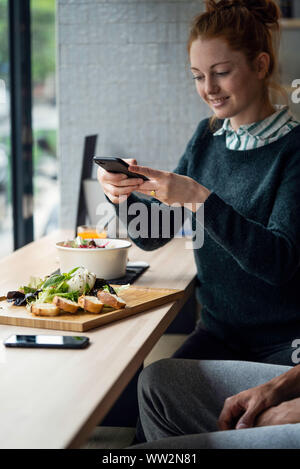 Young woman taking picture in restaurant Stock Photo