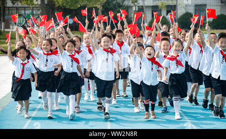 Young Chinese students wave Chinese national flags during a celebration event for the 70th anniversary of the founding of the People's Republic of Chi Stock Photo