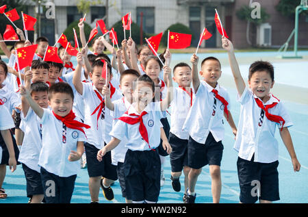 Young Chinese students wave Chinese national flags during a celebration event for the 70th anniversary of the founding of the People's Republic of Chi Stock Photo