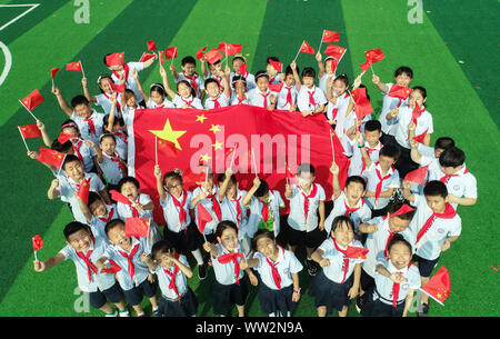 Young Chinese students wave Chinese national flags during a celebration event for the 70th anniversary of the founding of the People's Republic of Chi Stock Photo