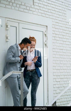 Couple using smart phone outdoors Stock Photo