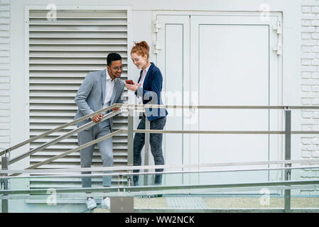 Couple using smart phone outdoors Stock Photo