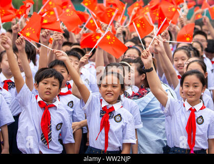 Young Chinese students wave Chinese national flags during a campaign to celebrate the 70th anniversary of the founding of the People's Republic of Chi Stock Photo