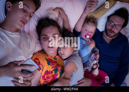 Family lying on bed at home Stock Photo