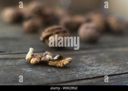 Whole and chopped walnuts on wooden table. Stock Photo