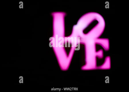 Abstact blurred Plastic pink sign of word LOVE on black background. Trendy 80s concept. Stock Photo