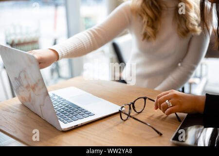 Close-up of two women working on project at modern coffee shop in city Stock Photo