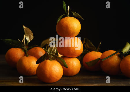 Tangerine pyramide with golden decorated leaves on dark background Stock Photo