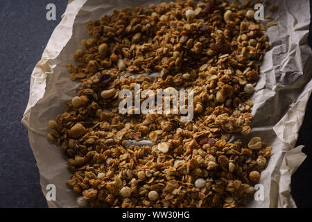 https://l450v.alamy.com/450v/ww30hg/top-view-of-roasted-granola-with-nuts-flakes-and-raisins-on-parchment-paper-close-up-texture-ww30hg.jpg