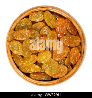 Sultanas, golden raisins, in wooden bowl. Big, golden-colored, dried grapes are eaten raw or used in cooking and baking. Close up, from above. Stock Photo