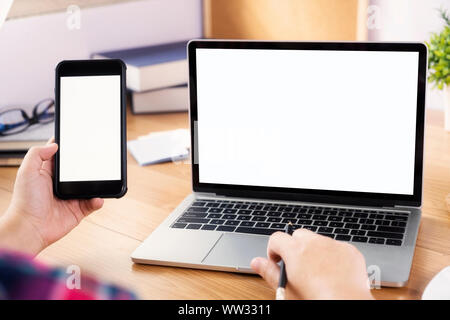 Closeup hands using smartphone mockup at the office desk. Blank screen mobile phone for graphic display montage. Stock Photo