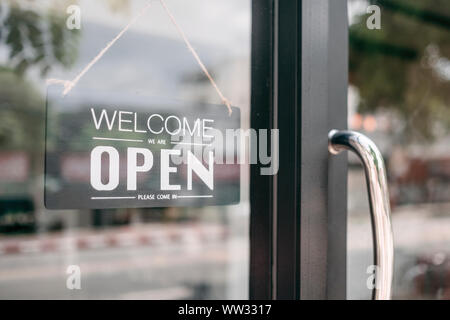 Closeup of open and welcome to store sign board hanging at the door. Open and welcome to store. New business Stock Photo