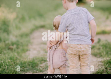 Big brother Helping Baby Sister to Walk in Nature Stock Photo