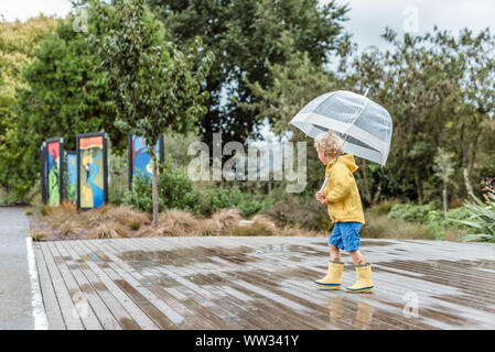 Child wearing rain boots and holding umbrella Stock Photo