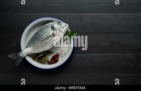 Bream in white plate on black background. Fish in black background. Top view. Copy space Stock Photo