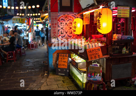 Taipei, Taiwan: Small street food stall at Raohe night market decorated with orange Japanese lanterns, selling seafood and Taiwan Beer Stock Photo