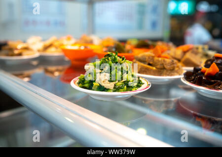Stir fired water spinach with tofu skin on small plate on glas table next to a variety of side dishes at a taiwanese Restaurant in Taipei Stock Photo