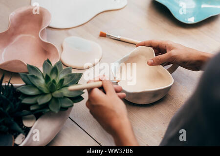 Hands of ceramist painting a bowl in studio Stock Photo
