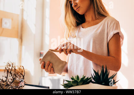 Woman artist molding a clay mug in her small studio Stock Photo