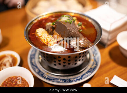 Taipei, Taiwan: Metal pot with spicy, chili hot pot soup with duck blood and stinky tofu. A traditional taiwanese dish. Stock Photo