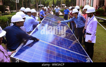 Engineers discussing about the solar photovoltaic cell during a solar power plant traing organised by GERMI in a sunny outdoor. Stock Photo