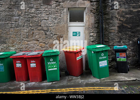 Wheelie bins in an alley with one blocking a fire escape. Stock Photo