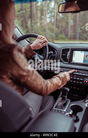 A woman in car, presses the emergency stop button, in the summer in the forest, automatic box, accident on the road, emergency stop mode, signaling to Stock Photo