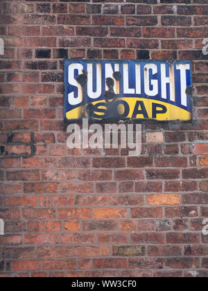 Old enamel Sunlight soap sign on red brick wall Stock Photo