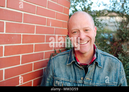 Portrait of smiling man in front of brick wall sunny day in California Stock Photo