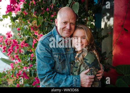 Happy dad hugging smiling daughter with red flowers Stock Photo