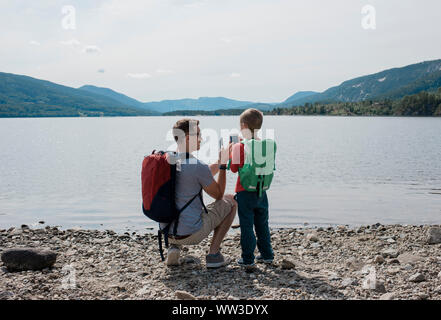 father and son taking pictures with cell phones of the mountains Stock Photo