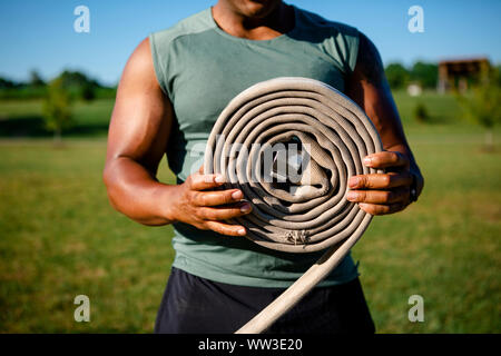 Close-up of an athletic man's hands holding a roll of frayed firehose Stock Photo