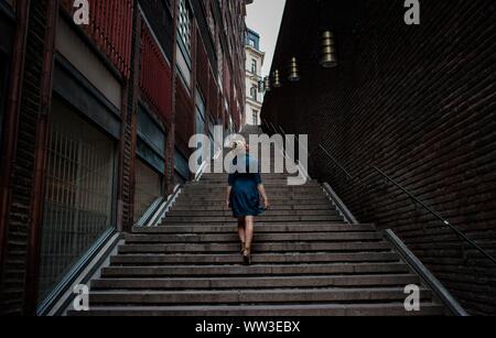 woman in a dress walking alone up many steps in the city centre Stock Photo